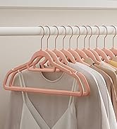 Plusieurs cintres en velours rose aux profils fins accrochés à une tringle de placard, pouvant contenir divers vêtements de couleur claire